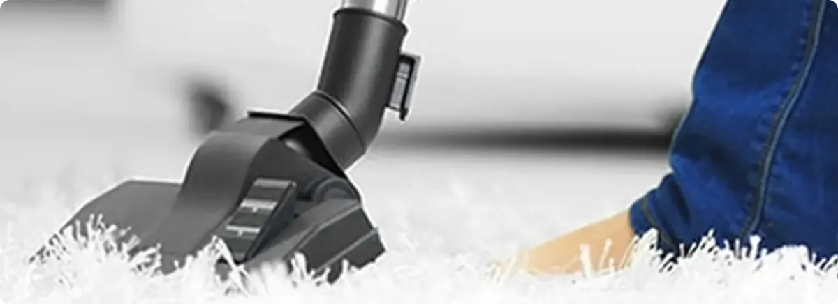 Close-up of a professional vacuuming a white carpet in Manchaca.